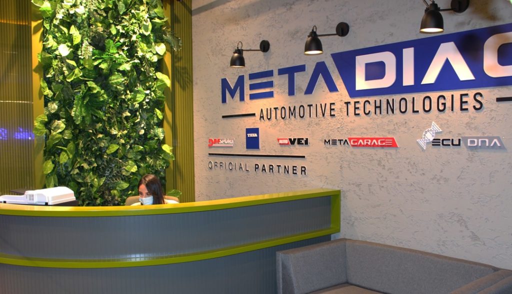 Reception area at MetaDiag Automotive Technologies with green wall and company branding.